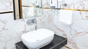 A bathroom with a white sink, a mirror, and a towel rack. - BENGALURU VISTA  (Ayodhya)
