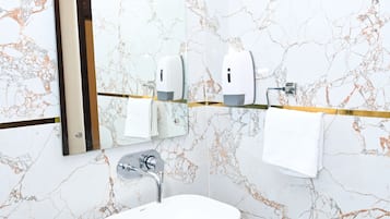 Un baño con lavamanos blanco, un espejo y un perchero para toallas.