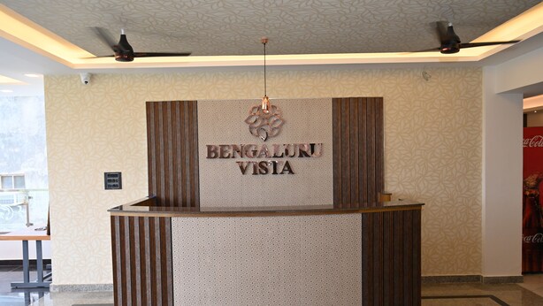 A reception desk with a sign that reads 'BENGALURU VISIA' and a patterned wall in the background. - BENGALURU VISTA  (Ayodhya)