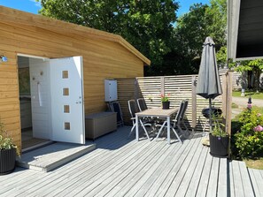 A wooden deck with a table and chairs, a small shed with an open door, and a potted plant.