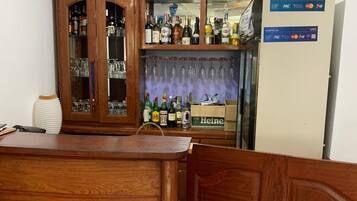 Zona de bar amb un taulell de fusta, un armari per a licors i un frigorífic amb un terminal de pagament.