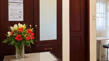 A reception desk with a vase of flowers, a framed certificate, and a remote control on a table.