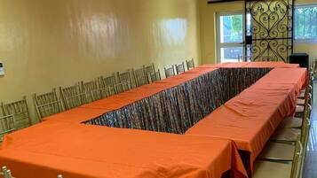Un salón de conferencias con una larga mesa, sillas y una vista decorativa a la ventana.