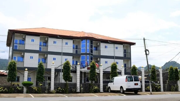 A multi-story building with a flat roof, a white facade, and a series of balconies. - Hotel Omnisport (Limbe)
