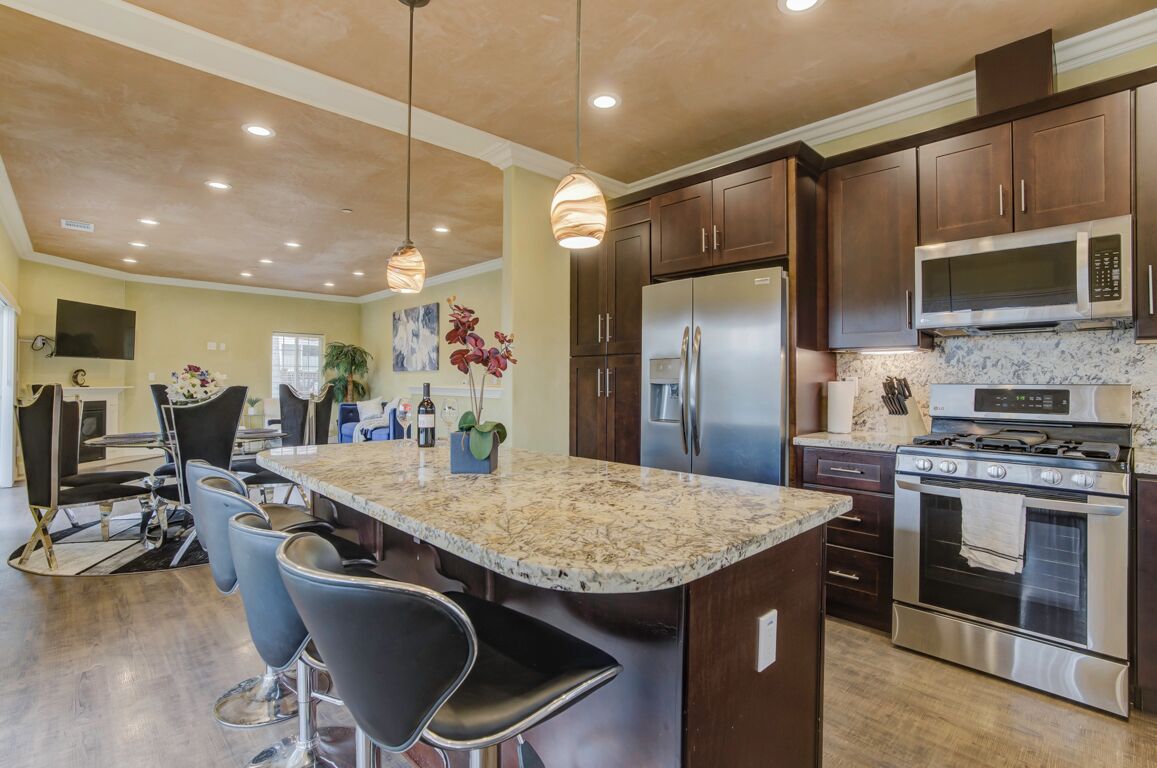 A modern kitchen with dark wood cabinets, stainless steel appliances, and a central island with bar stools.