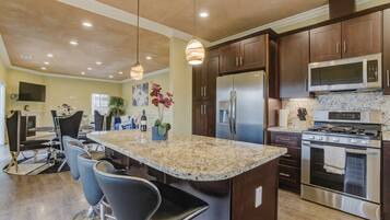 A modern kitchen with dark wood cabinets, stainless steel appliances, and a central island with bar stools.