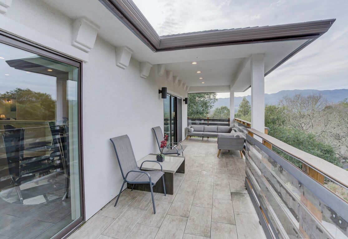 Un espacio al aire libre cubierto con mesa y sillas, un sofá y vistas al paisaje.