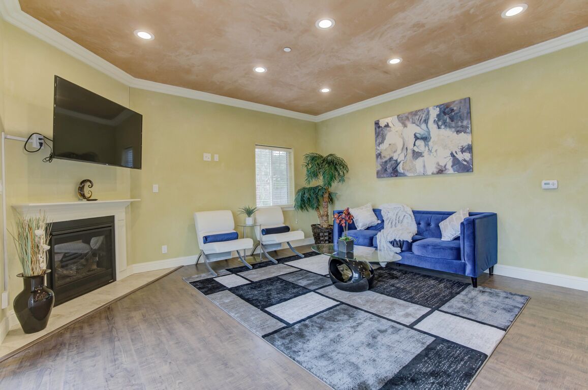 A living room with a fireplace, a blue sofa, a coffee table, and a large abstract painting.