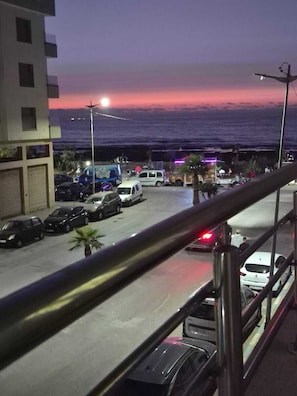 A parking area with vehicles and a view of the ocean at dusk. - Adorable 2-bedroom apartment with AC in welcoming Mohammedia (Mohammedia)