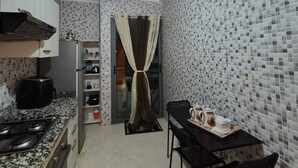 Una cucina compatta con piano cottura a gas, una macchina da caffè e un'area pranzo con tavolo e sedie.