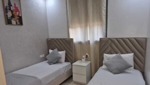 Camera d'albergo con due letti singoli, un piccolo comodino con un vaso e un quadro appeso al muro.