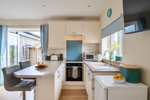 A compact kitchenette with a dining area, a microwave, a toaster, and a sink. - Ashclose Lodge Annexe -  Sherborne, Dorset (Sherborne)