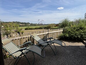 A patio with two striped lounge chairs and a wooden fence. - Ashclose Lodge Annexe -  Sherborne, Dorset (Sherborne)