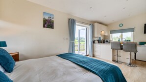Ein Schlafzimmer mit einem Bett, Blick auf die Küche und einem Essbereich mit Stühlen.