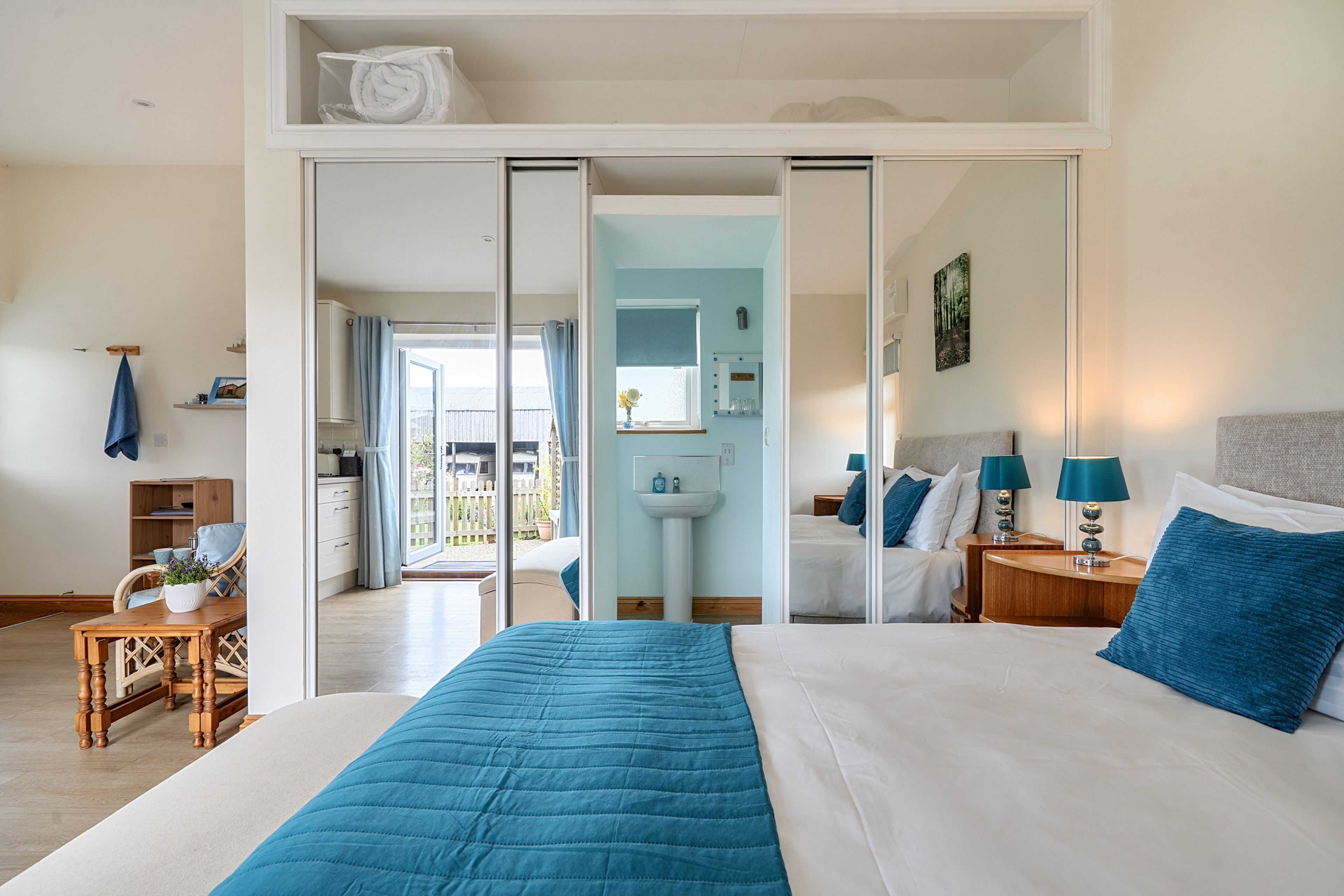 Quarto de hotel com cama, escrivaninha, cadeira, banheiro e vista para o exterior.