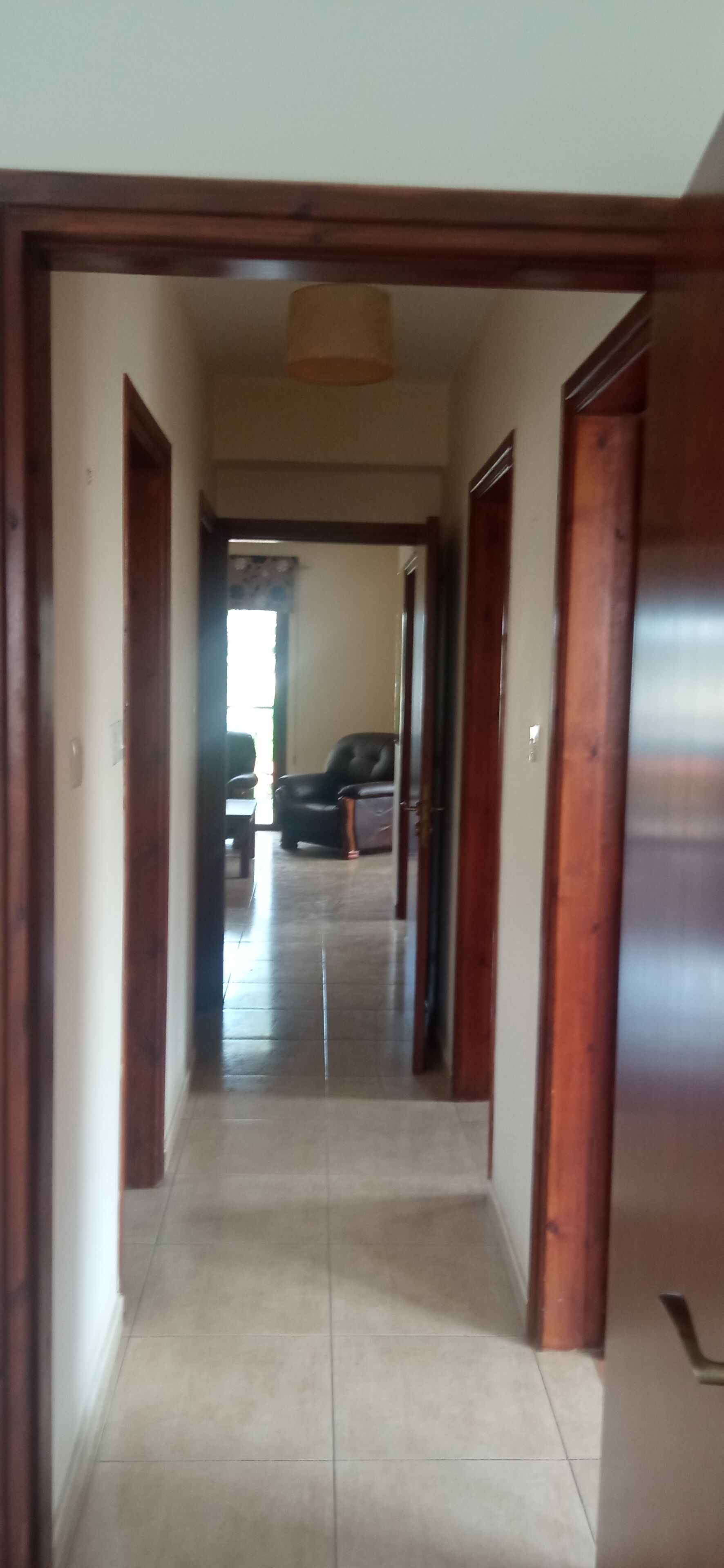A hallway with a door on the right, leading to a room with a chair and a table.