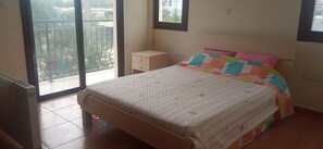 Un dormitorio con cama, mesita de noche, ventana y radiador.