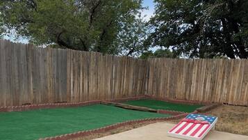 Two GoSports bean bag chairs with American flag designs, set on a concrete patio with a wooden fence and green artificial turf in the background.
