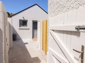 Un sendero estrecho que conduce a una pequeña construcción con una puerta y un ventanal.