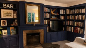 A room with a fireplace, bookshelves, a television, and a sofa. - House in Yvoire between Lake and Village (Yvoire)