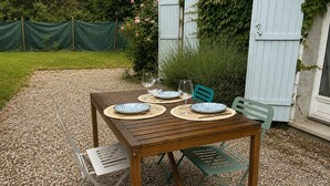 A wooden table set with plates and glasses, surrounded by pebbles. - House in Yvoire between Lake and Village (Yvoire)
