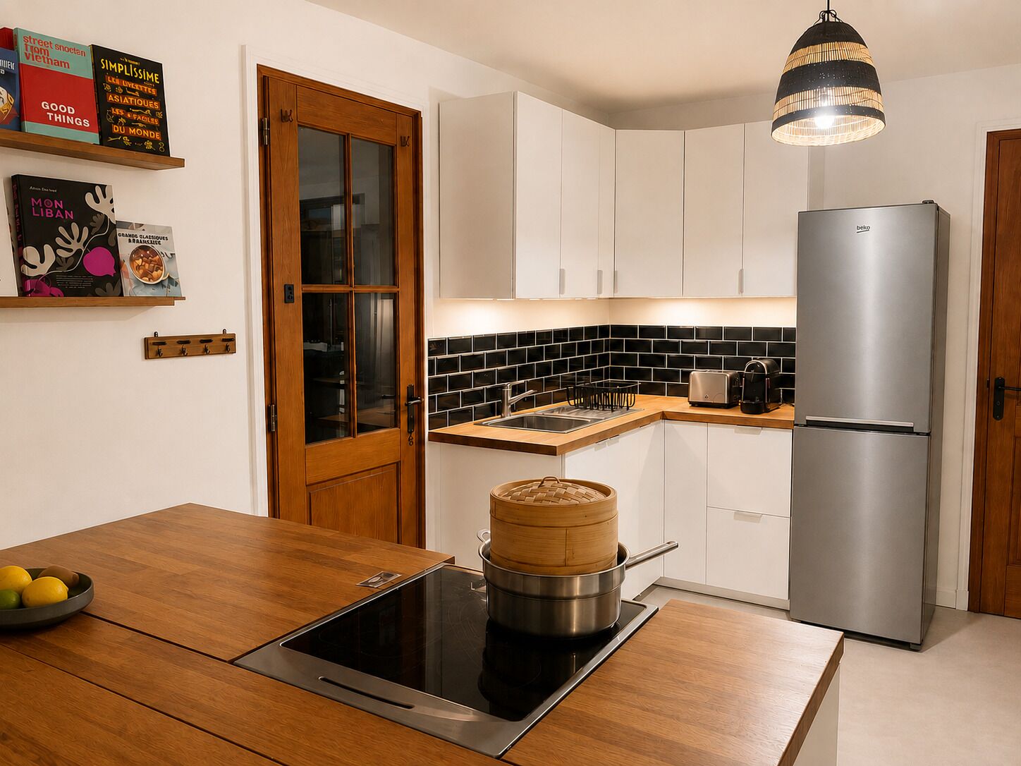 A modern kitchen with a built-in stove, a stainless steel refrigerator, and a wooden dining table.