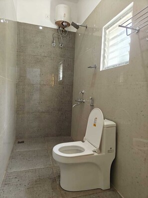 A bathroom with a toilet, a shower, and a towel rack.