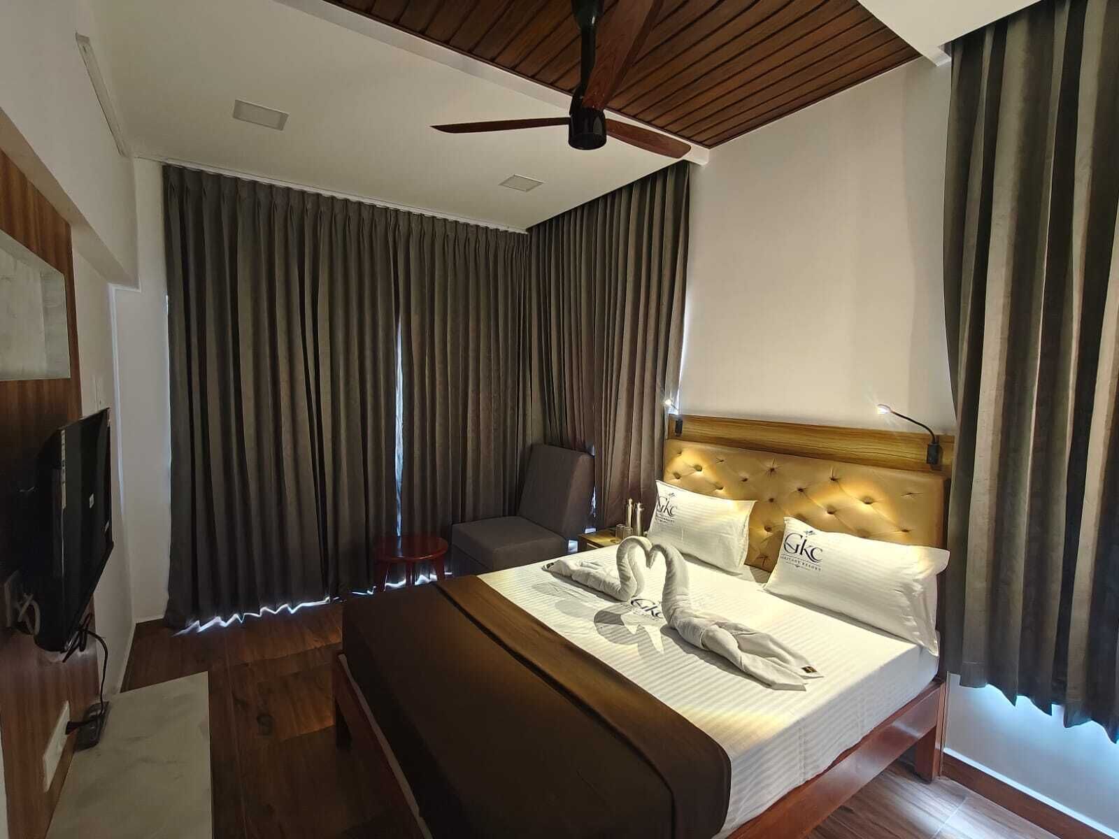 Una habitación de hotel con cama, televisión, ventilador de techo y vistas al exterior.