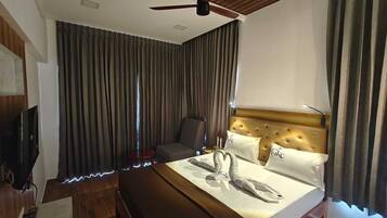 Una habitación de hotel con cama, televisión, ventilador de techo y vistas al exterior.