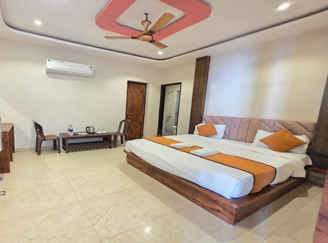Habitación de hotel con cama, escritorio, silla, ventilador de techo y aire acondicionado.