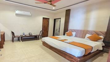Habitación de hotel con cama, escritorio, silla, ventilador de techo y aire acondicionado.