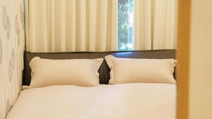 A bed with a headboard and two pillows, a window with curtains, and a partial view of a wall. - Direct train access to 道頓堀 黒門市場 USJ Kyoto Temmabashi Blue Sky Guesthouse (Osaka)
