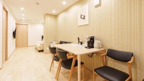 A hotel room with a wooden floor, a dining table with chairs, a coffee maker, and a TV mounted on the wall. - Direct train access to 道頓堀 黒門市場 USJ Kyoto Temmabashi Blue Sky Guesthouse (Osaka)