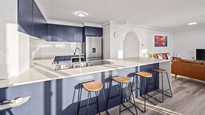 Eine moderne Küche mit Kochinsel, Barhocker, Kühlschrank und Mikrowelle.