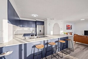 A modern kitchen with a central island, bar stools, a refrigerator, and a microwave. - "HAVEN" By TheGuestHouse. (Broadbeach)