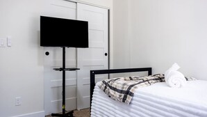 Een slaapkamer met een bed, een televisie op een standaard en een handdoek op het bed.