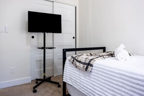 Ein Schlafzimmer mit einem Bett, einem Fernseher auf einem Schrank und einem Handtuch auf dem Bett.