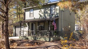 Een twee verdiepingen tellend huis met een veranda, een Amerikaanse vlag en een garage.