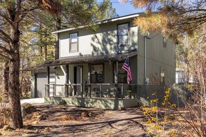 Ein zweistöckiges Haus mit Veranda, einer amerikanischen Flagge und einer Garage.