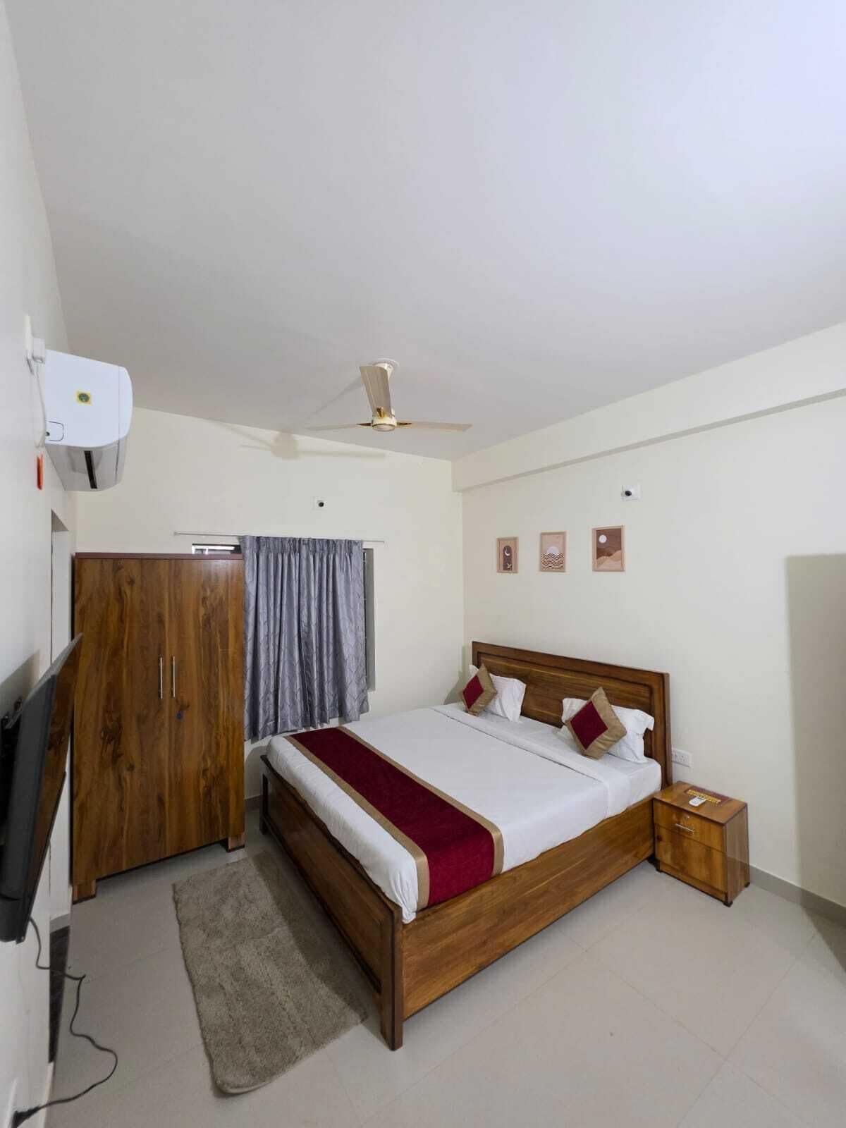 A bedroom with a bed, a wardrobe, a ceiling fan, and a small bedside table.