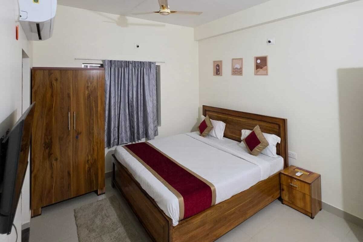 A bedroom with a bed, a wardrobe, a ceiling fan, and a small bedside table.