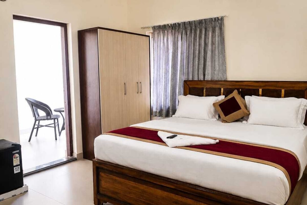 A bedroom with a bed, a wardrobe, a ceiling fan, and a view of the outside.