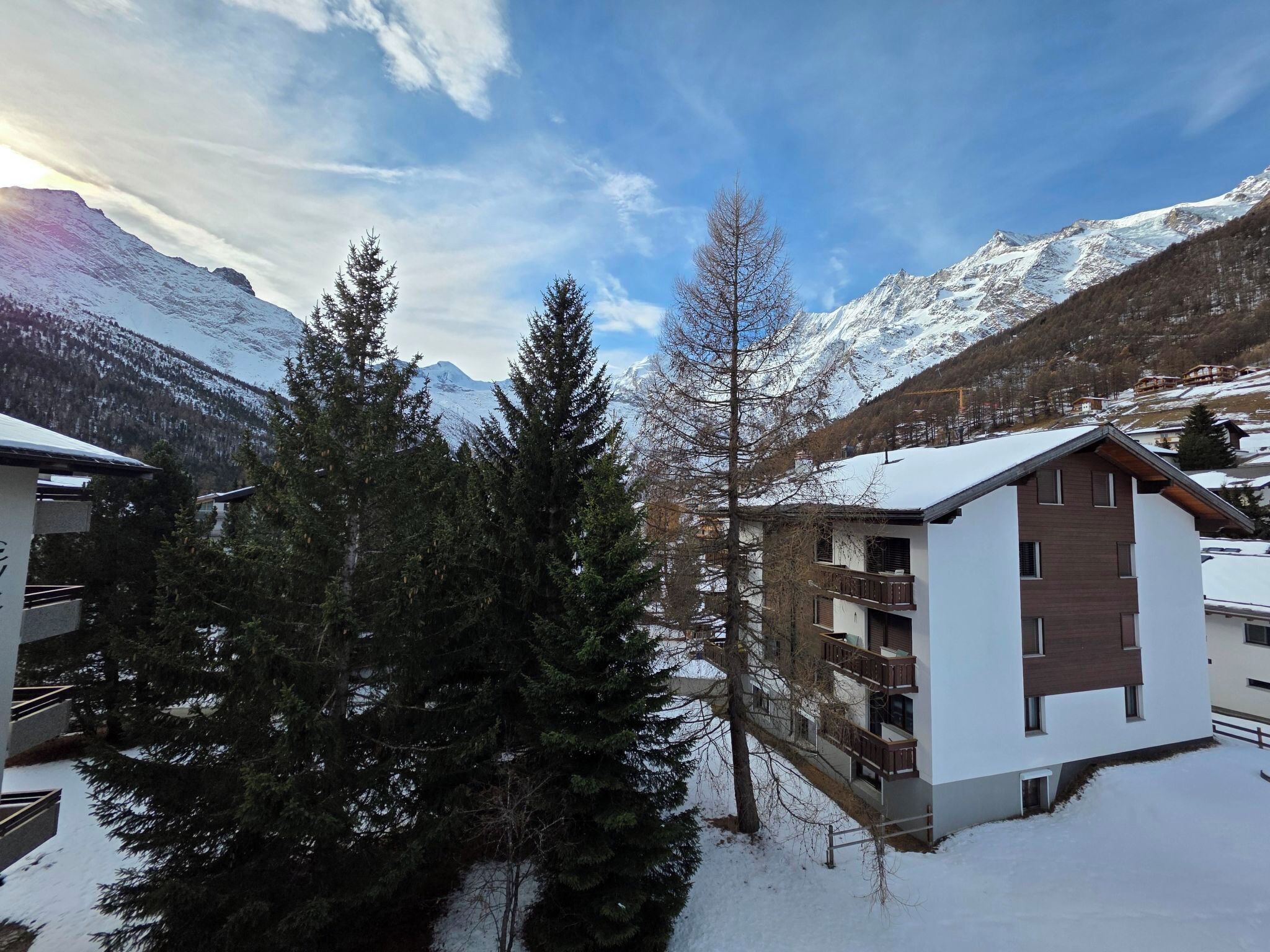 Paisatge de muntanya amb neu, edificis i arbres.