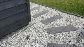 A grassy outdoor area with a wooden deck and a gravel path leading to a building. - Aelia in Peregian Beach (Peregian Beach)