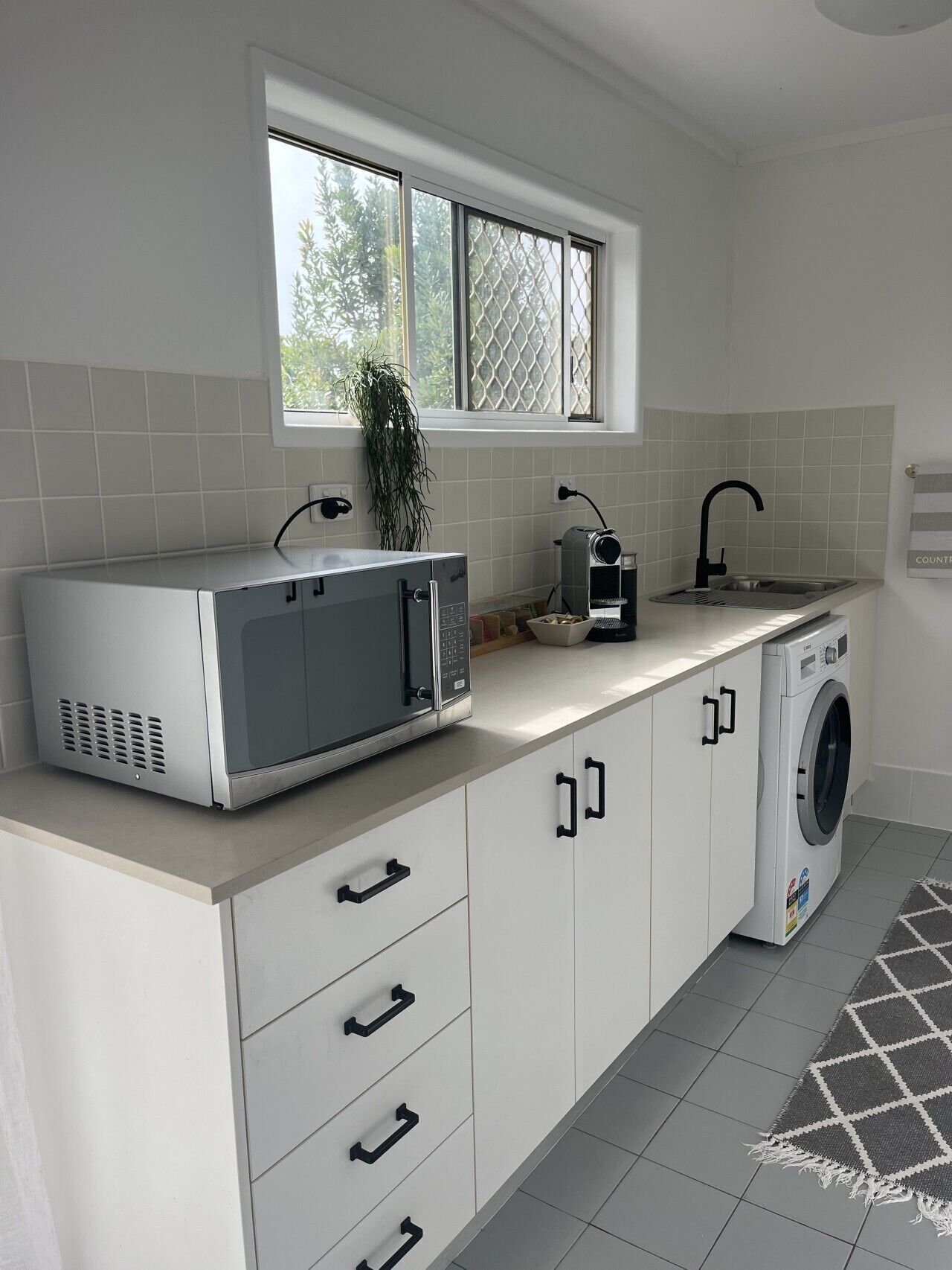 A kitchen with a microwave, sink, and washing machine.