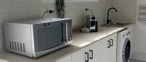 A kitchen with a microwave, sink, and washing machine.