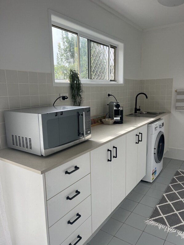 A kitchen with a microwave, sink, and washing machine.