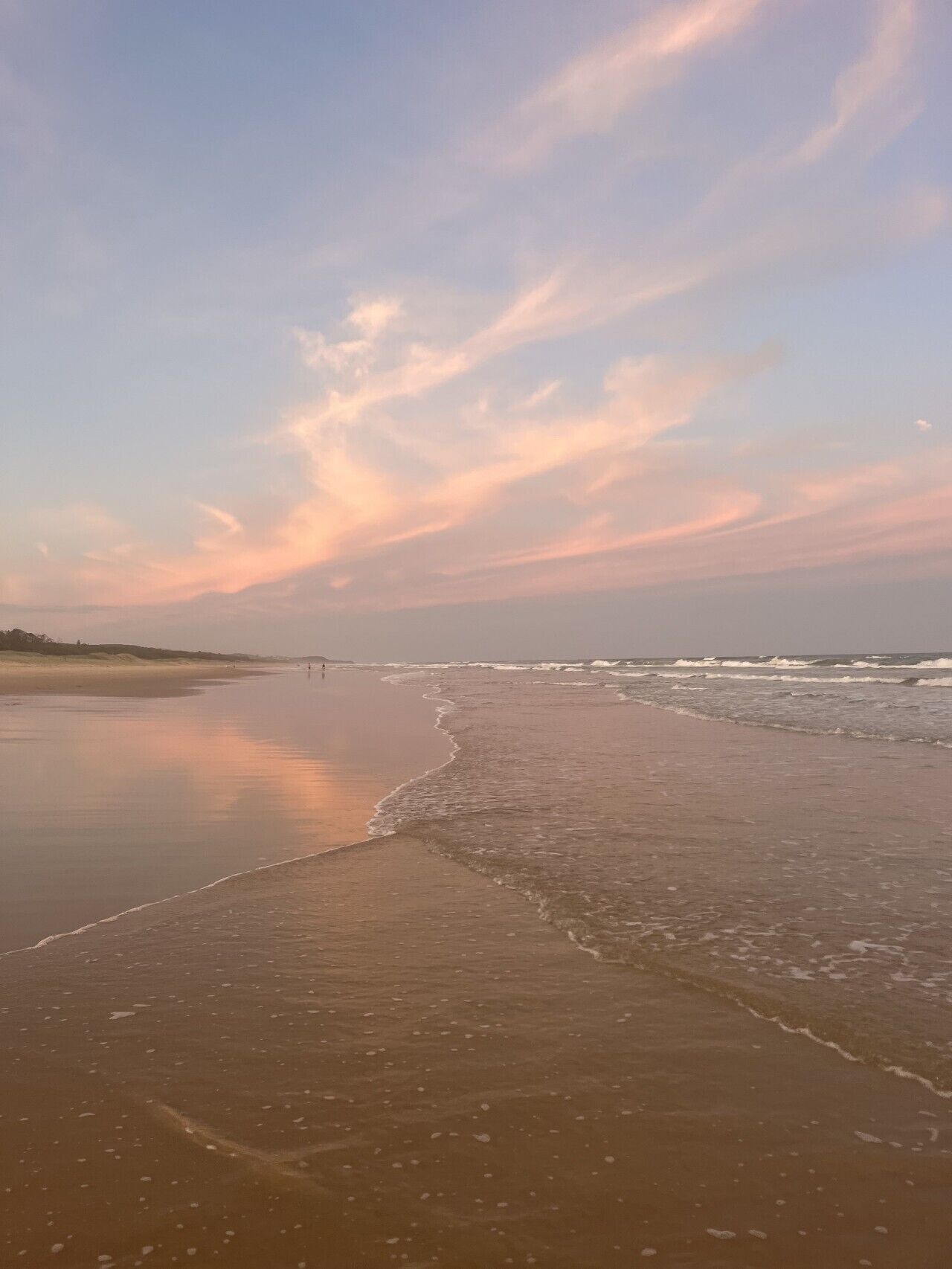 Een strand met een breed zandstrand en rustige golven.