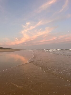 A beach with a wide sandy shore and gentle waves.