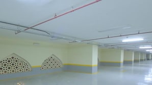 Ruime overdekte parkeerplaats met duidelijke zichtlijnen, kolommen en een nette vloer.